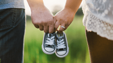 Married couple holding baby shoes