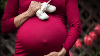 Pregnant mother holding baby shoes